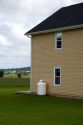 Propane fuel tank outside a house with supply line.