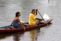 Brazilian man and woman in a canoe on the Arasa River in the Amazon jungle near Manaus, Brazil.