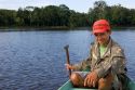 Brazilian man in a dugout canoe on the Arasa River in the Amazon jungle near Manaus, Brazil.