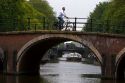 Man riding a bicycle crossing a brige over a canal near the Amstel River in Amsterdam, Netherlands.