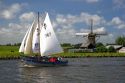 Sailing past a windmill on a canal east of Leiden in the province of South Holland, Netherlands.