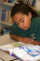 Fourth grade hispanic female student reads a textbook in a classroom at a public school in Tampa, Florida.