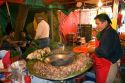 Vendor cooking cabeza tacos using a cazo at the Merced Market in Mexico City, Mexico.