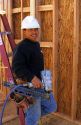 Hispanic construction worker wearing a hard hat and holding a pneumatic nail gun in Boise, Idaho. MR