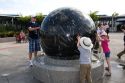 Visitors push the Constellation Sphere, a 9 ton granite sphere floating on water at the Kennedy Space Center Visitor Complex in Cape Canaveral, Florida.
