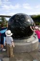 Children push the Constellation Sphere, a 9 ton granite sphere floating on water at the Kennedy Space Center Visitor Complex in Cape Canaveral, Florida.