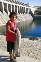 Colville Native American Indian boy with large Chinook Salmon at Chief Joseph Dam in Washington.