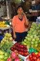Vendor selling produce and speaking on a cell phone at a market in the Cholon district of Ho Chi Minh City, Vietnam.