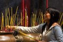 Vietnamese woman burning incense at the Quan Am Pagoda, a famous Chinese temple in the Cholon district of Ho Chi Minh City, Vietnam.