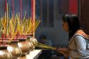 Vietnamese woman burning incense at the Quan Am Pagoda, a famous Chinese temple in the Cholon district of Ho Chi Minh City, Vietnam.