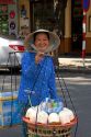 Vietnamese woman selling coconuts and bottled water on the street in Ho Chi Minh City, Vietnam.
