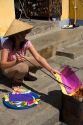 Vietnamese woman burning colorful paper to honor departed ancestors during Tet in Hoi An, Vietnam.