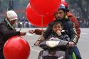 Vietnamese family on a motorbike purchase a balloon from a street vendor in Hanoi, Vietnam.