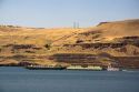 Barges being pushed down the Columbia River by a tugboat near the John Day Dam, Oregon, USA.