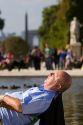 Man sunbathing near a fountain at the Tuileries Garden near the Lourve in Paris, France.