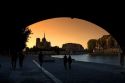 View of the Notre Dame cathedral at sunset through the arch of the Tournelle Bridge on the River Seine in Paris, France.