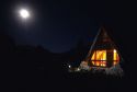 A-frame cabin lit up at night in the Andes mountain range in Chile.