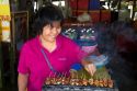 Woman grilling satay at an open air market on the island of Ko Samui, Thailand.
