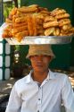 Vietnamese street vendor balances baked sweet snacks on his head in Nha Trang, Vietnam.