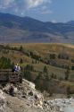 Tourists stand at a scenic overlook near Mammoth Hot Springs in Yellowstone National Park, Wyoming, USA.