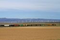 Union Pacific Railroad train traveling past a line of wind powered electric generators in Elmore County, Idaho, USA.