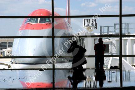 Travelers using cell phones at the Detroit Metro Airport in front of a Boeing 747.