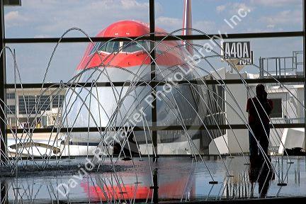 Boeing 747 airliner parked at the gate of Detroit Metropolitan airport near an indoor fountain.