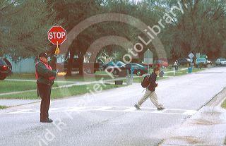 School crossing guard with child walking on crosswalk. MR
