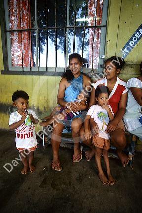 Native Tahitian woman and children in front of a store in Fare, Huahine, Tahiti.