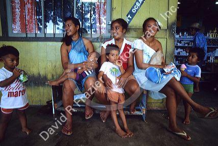 Native Tahitian women and children in front of a store in Fare, Huahine, Tahiti.