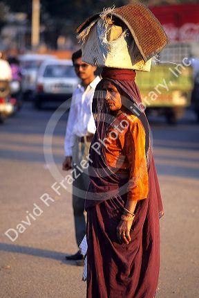 Indian woman carrying a box atop her head in Delhi, India.