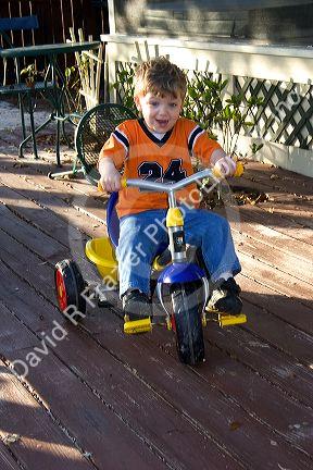 A three year old boy riding a tricycle in Florida. MR