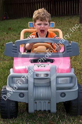 Three year old boy riding in a battery powered toy car. MR