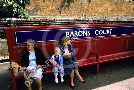 People sitting at a subway train stop in London, England.