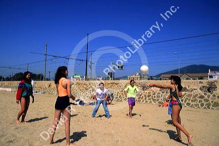 Teens play volleyball on the beach in Spain.