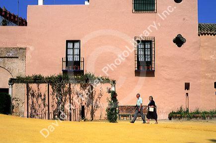 An elderly couple walk near the Alcazar of Seville, Spain.