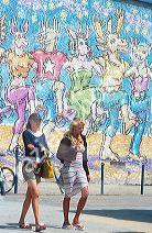 Mural with girls walking in front of it in Venice Beach, California.