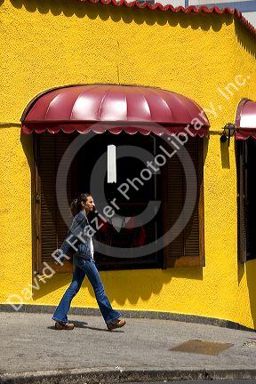 Woman walking in front of a brightly colored building in Sao Paulo, Brazil.