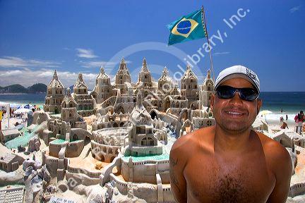 A sandcastle and its sculptor on the Copacabana Beach in Rio de Janeiro, Brazil.