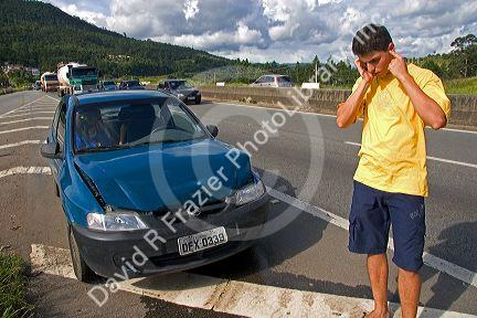 Brazilian man on a cell phone at the scene of a traffic accident near Sao Paulo, Brazil.