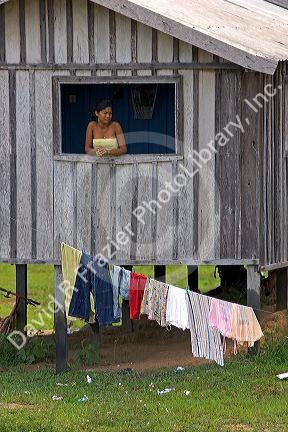 Brazilian girl looking out the window of her house in the Amazon jungle near Manaus, Brazil.