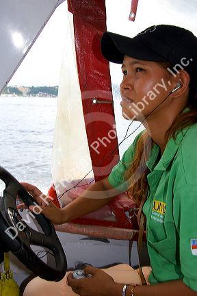 Brazilian woman listens to an MP3 player while driving an Amazon river boat at Manaus, Brazil.