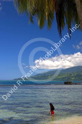 Tahitian woman entering in the lagoon on the island of Tahiti.