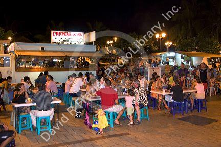 Outdoor dining in a plaza among roulotte food vans at Papeete on the island of Tahiti.