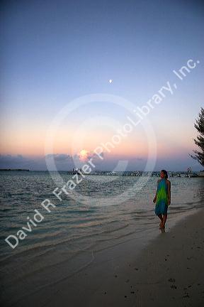 Woman walking on the beach at dusk on the island of Moorea. MR