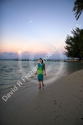 A woman walking on the beach at dusk on the island of Moorea. MR