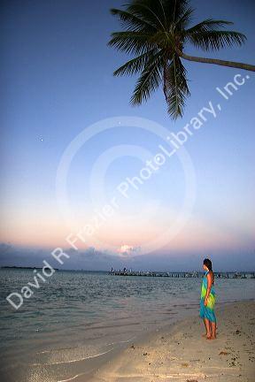 Woman walking on the beach at dusk on the island of Moorea. MR