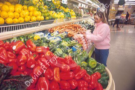 Young girl shopping for vegetables at a grocery store.