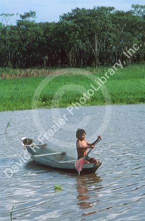 Brazillian boy rows a canoe on a tributary of the Amazon River in Manaus, Brazil.