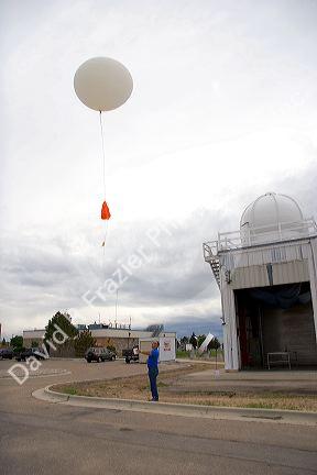 Meteorologist launching a weather balloon with a radiosonde sensor at the National Weather Service in Boise, Idaho.